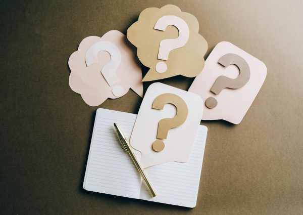 Flat lay of question mark paper crafts on a notebook, symbolizing questions and ideas.